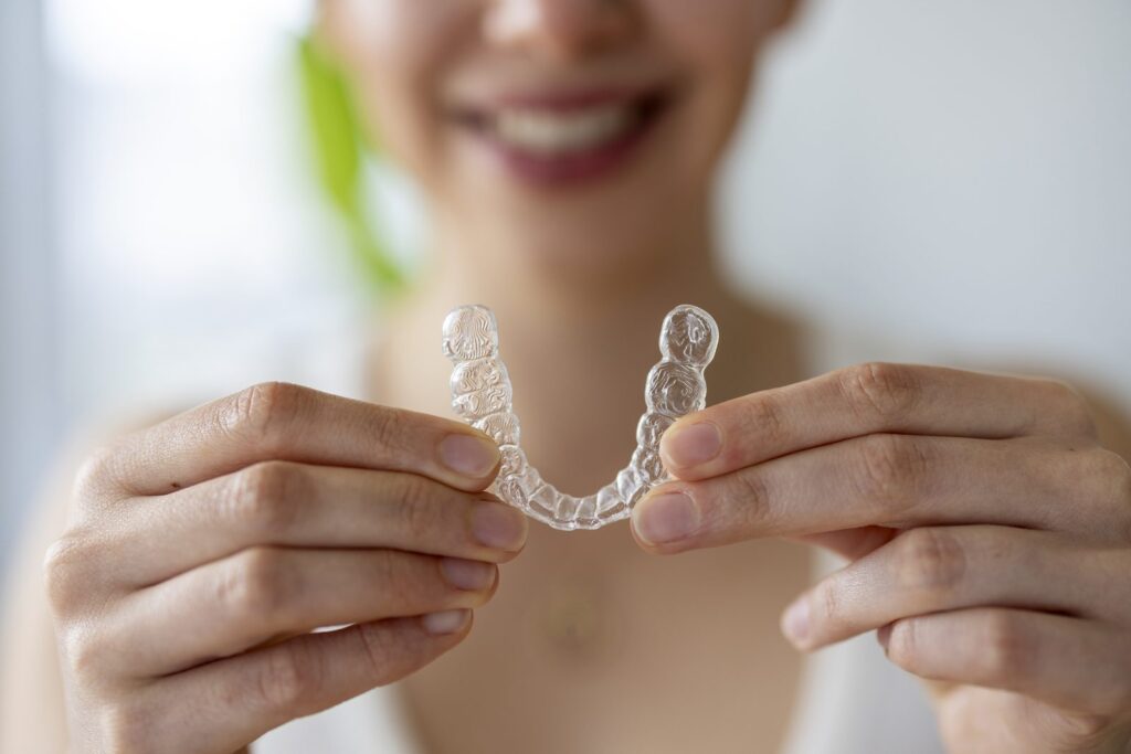 Hands holding a clear Invisalign aligner – Invisalign Lite for minor cases